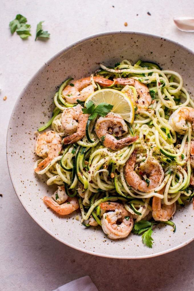 low-carb garlic shrimp zoodles in a bowl with slice of lemon