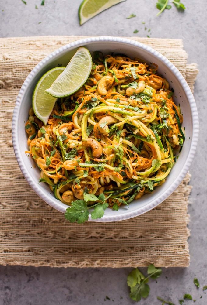 bowl of garlic lime cashew zoodles with lime wedges