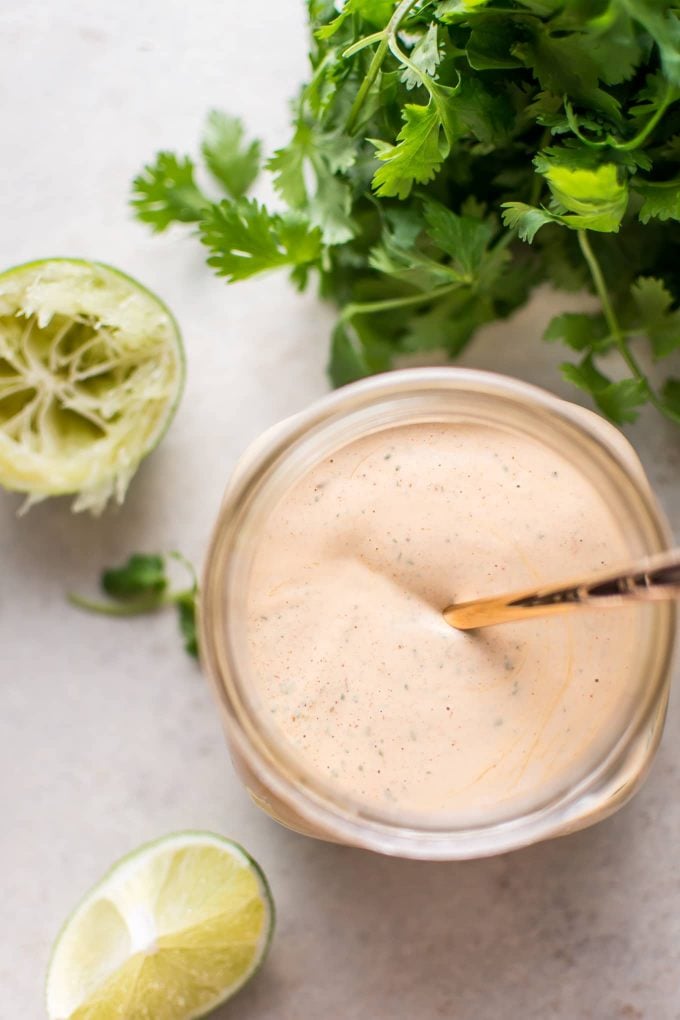 mason jar with chipotle lime cilantro ranch dressing and a squeezed lime with a cilantro bunch