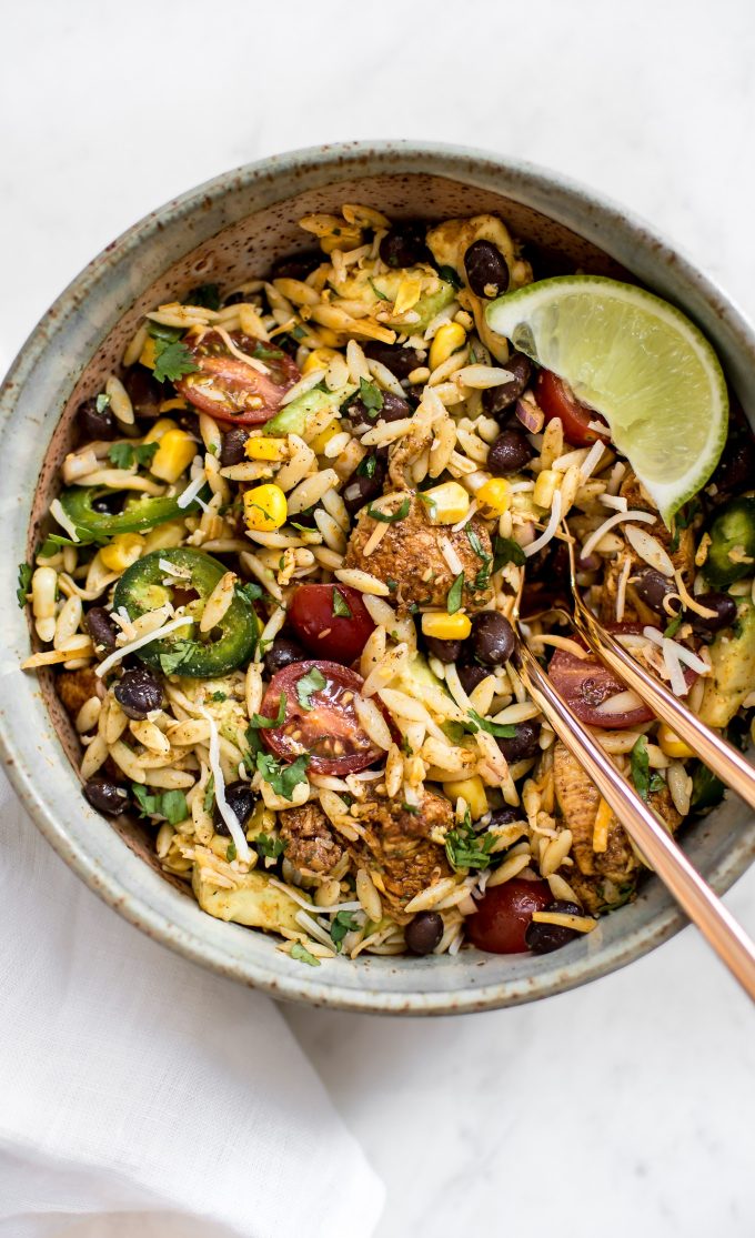healthy Mexican chicken salad with orzo in a bowl with rose gold utensils