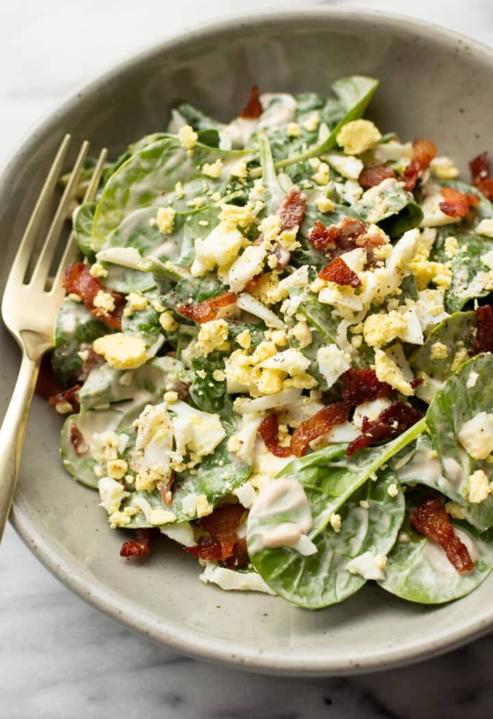 a bowl with spinach salad with a fork