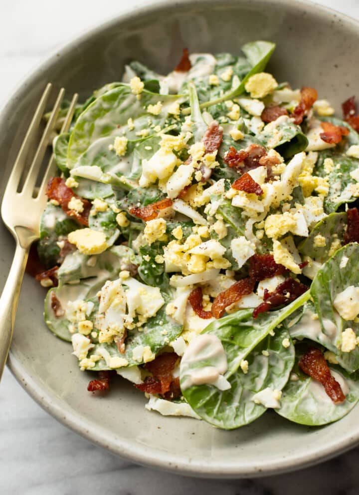 a bowl with spinach salad with a fork