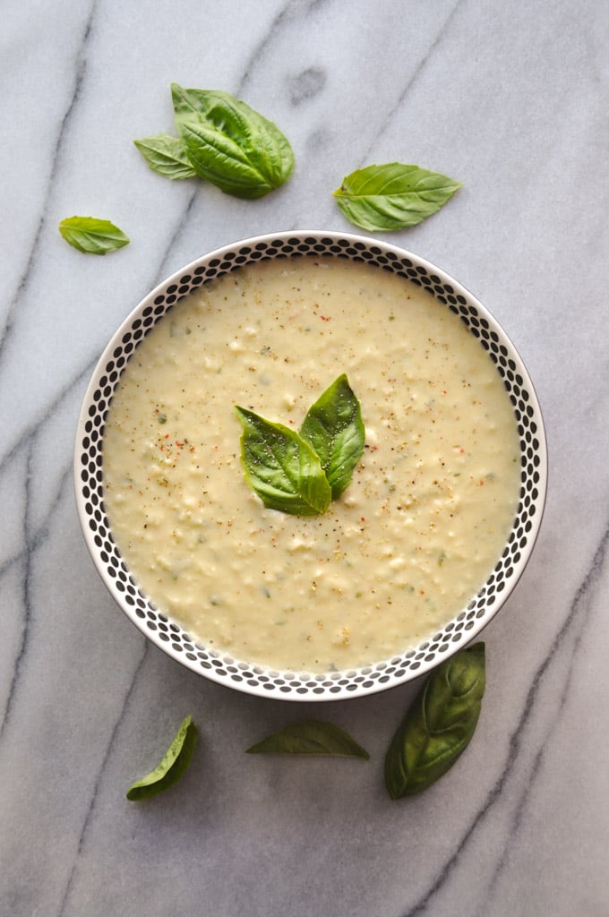 vegetarian white bean dip in a bowl beside basil leaves on a marble surface