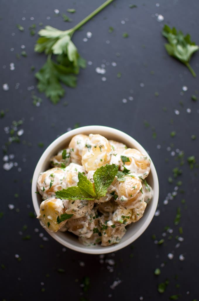 bowl of creamy baby potato salad with fresh herbs and mint garnish