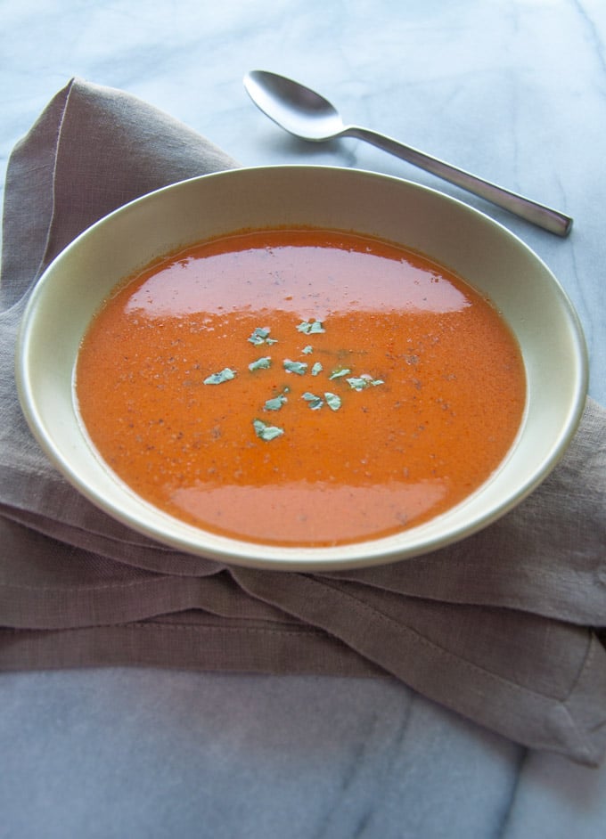 bowl of healthy roasted tomato soup with tarragon and a spoon