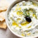 easy tzatziki sauce with an olive, oil drizzled on top, and pita bread
