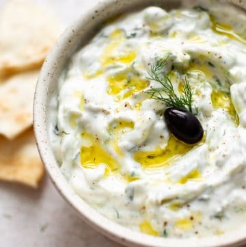 easy tzatziki sauce with an olive, oil drizzled on top, and pita bread