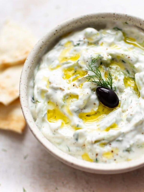 easy tzatziki sauce with an olive, oil drizzled on top, and pita bread