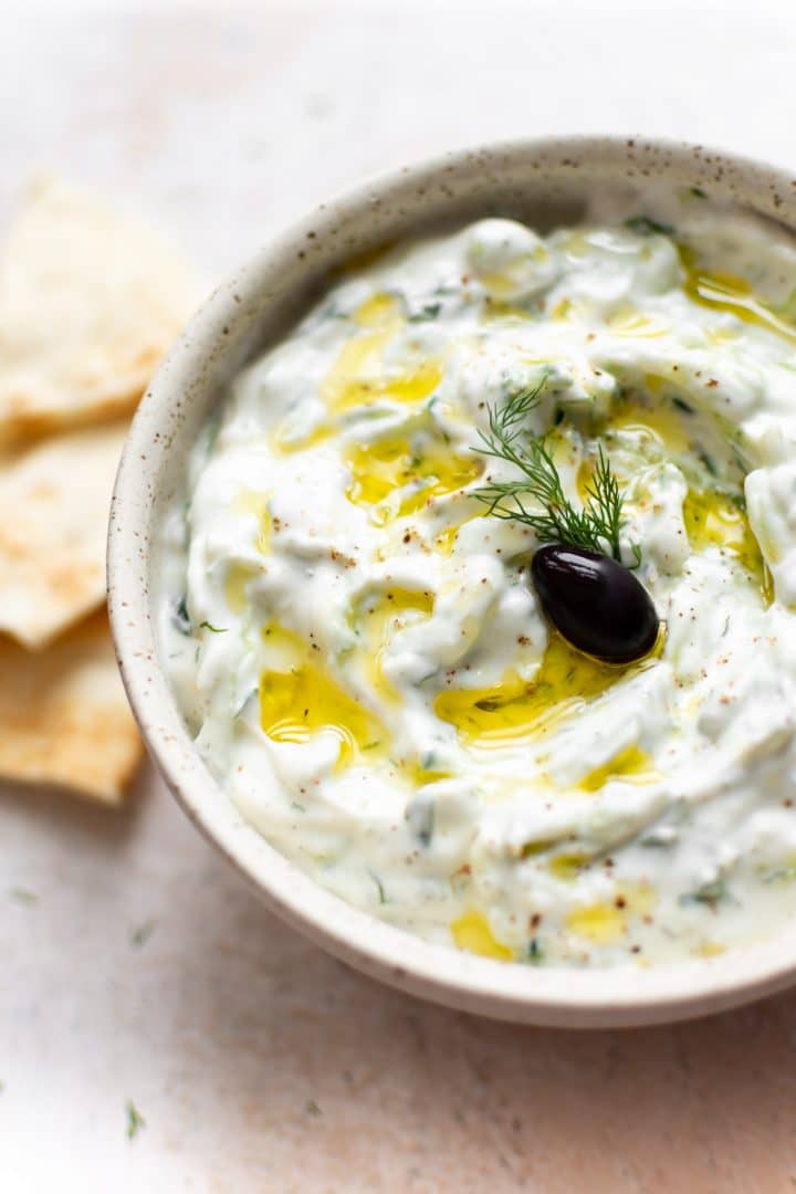 easy tzatziki sauce with an olive, oil drizzled on top, and pita bread