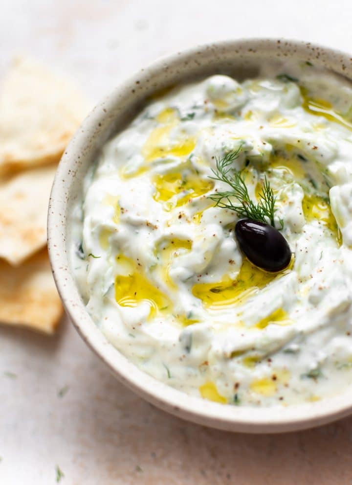easy tzatziki sauce with an olive, oil drizzled on top, and pita bread