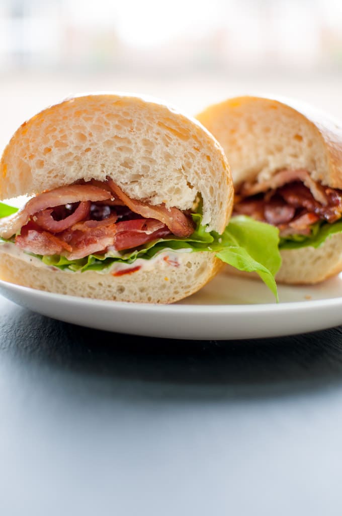 BLT with garlic and sun-dried tomato mayo cut in half on a plate