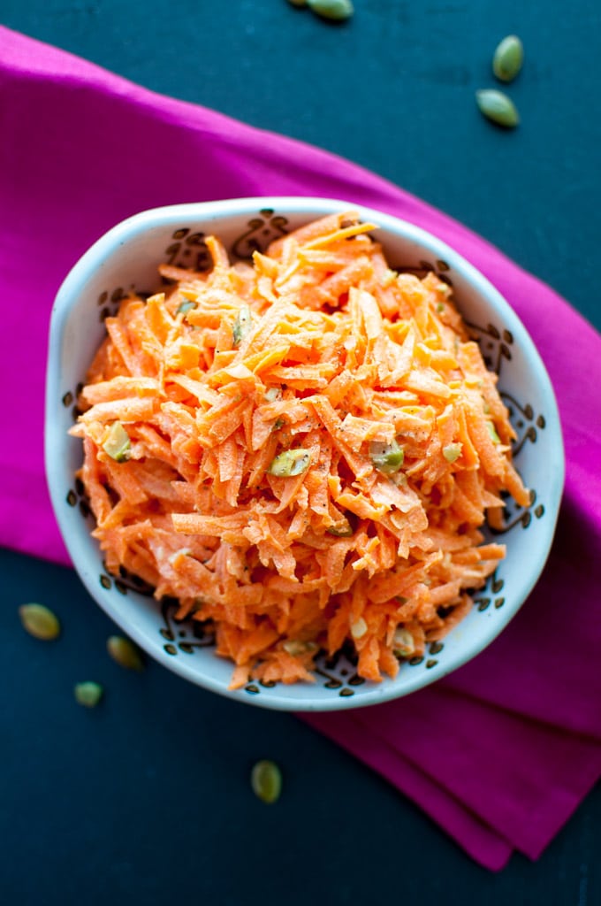 bowl with carrot salad with pumpkin seeds on a pink cloth napkin