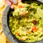 homemade guacamole in a molcajete being scooped by a tortilla chip