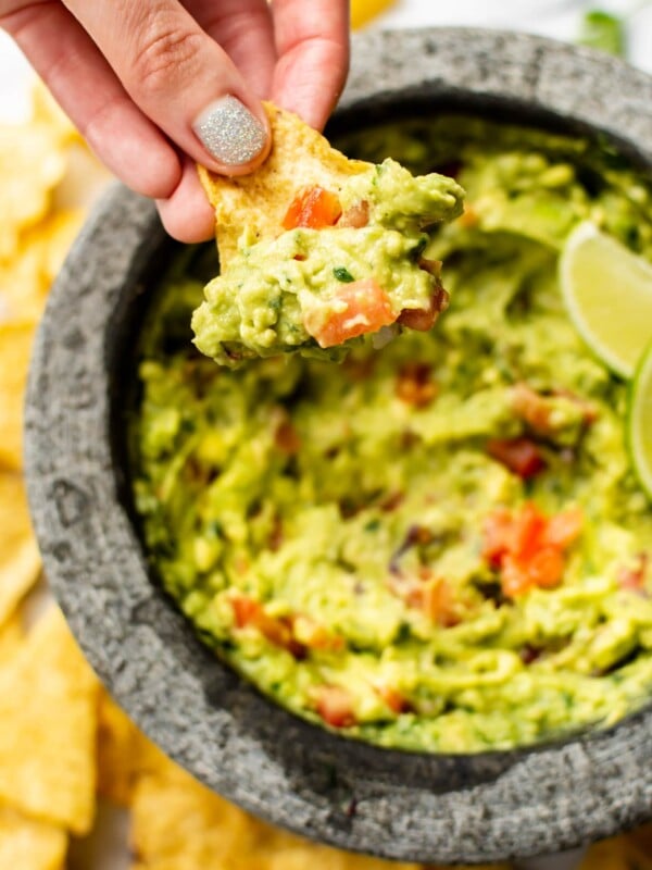 homemade guacamole in a molcajete being scooped by a tortilla chip