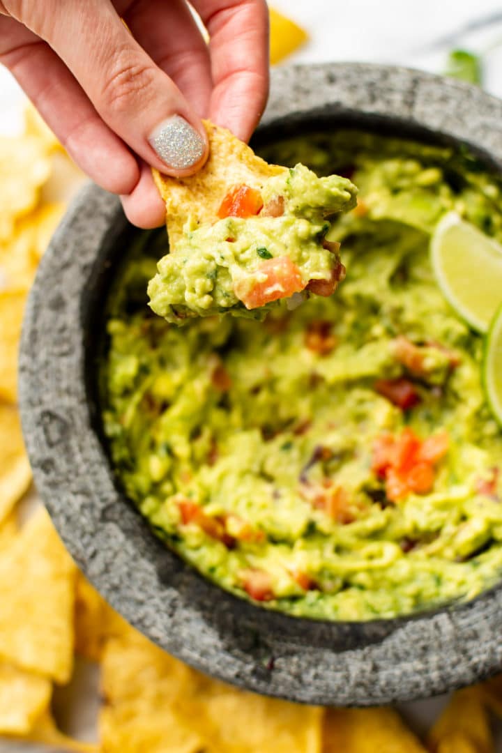 homemade guacamole in a molcajete being scooped by a tortilla chip