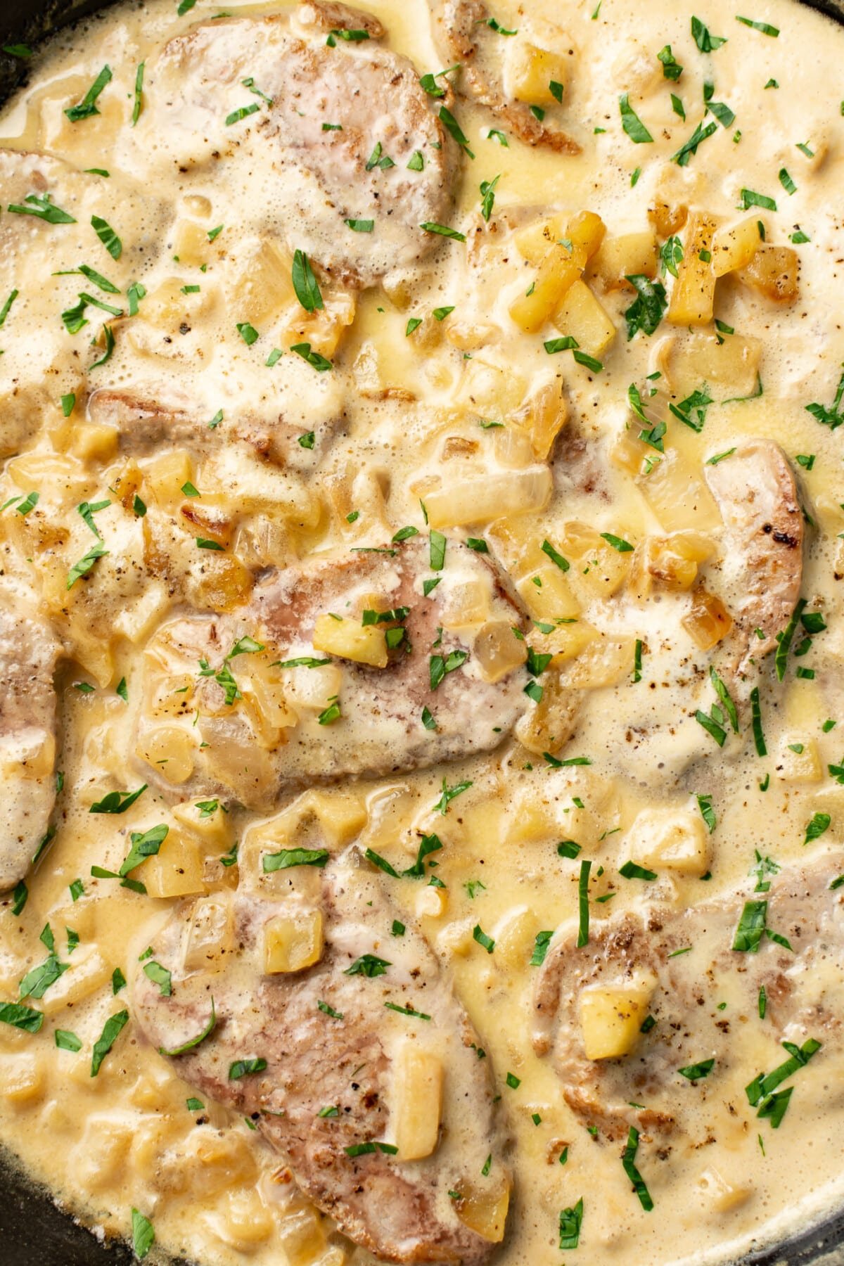 closeup of a skillet with pork in a creamy brandy apple sauce