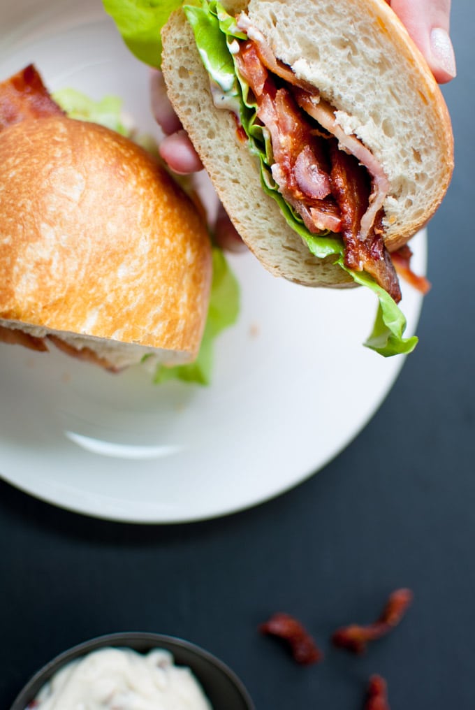 close-up of a hand holding half a BLT with garlic and sun-dried tomato mayo