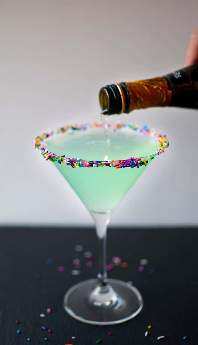 martini glass with Sprinkletini and champagne being poured into it