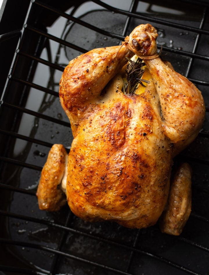 whole roasted chicken in a roasting pan on a rack