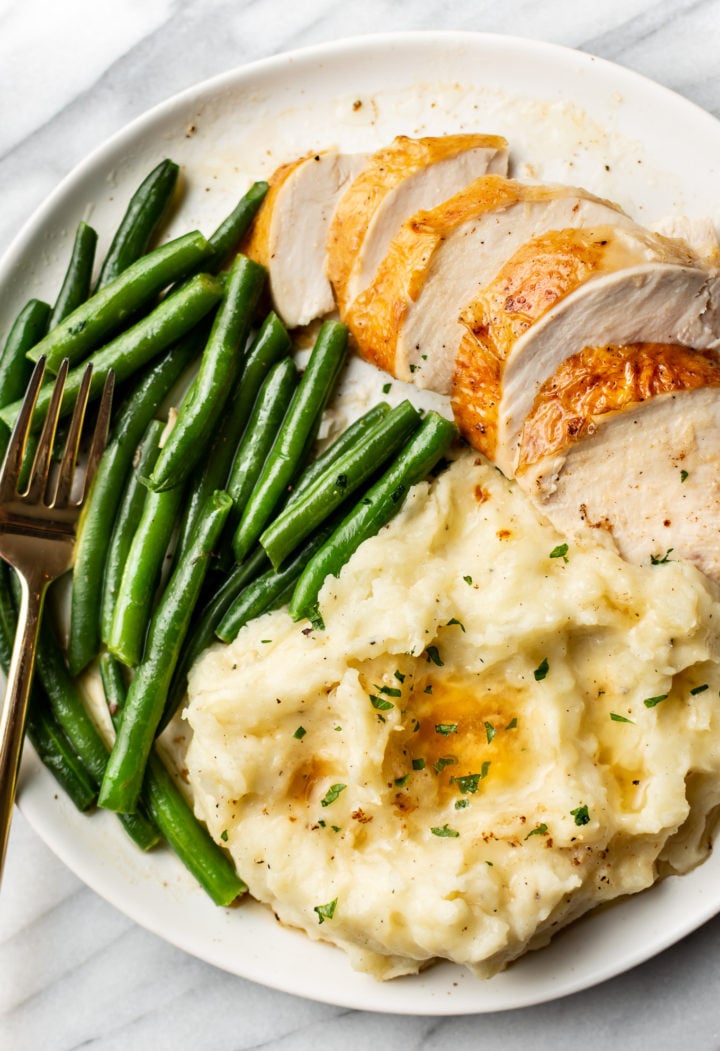 perfect roasted chicken carved and plated with mashed potatoes and green beans