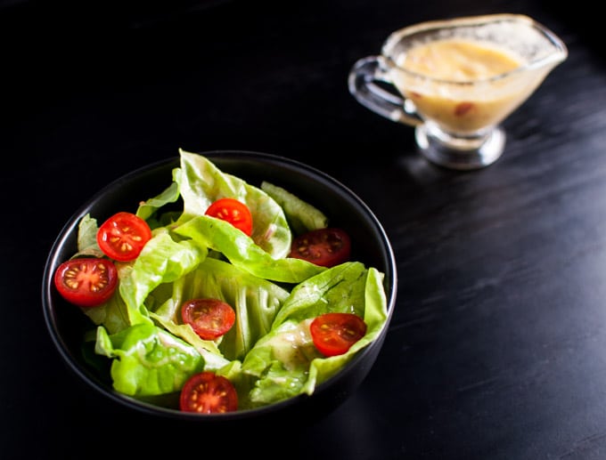 black salad bowl with iceberg lettuce, tomatoes, and the best vinaigrette