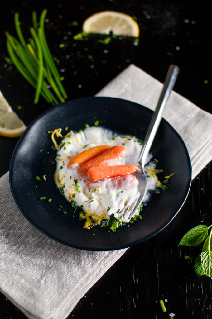 close-up of a bowl of carrots with herbed yogurt and a fork