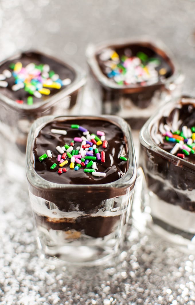 close-up of an Oreo, Reese\'s, Cool Whip, and chocolate mini layered dessert in a glass container