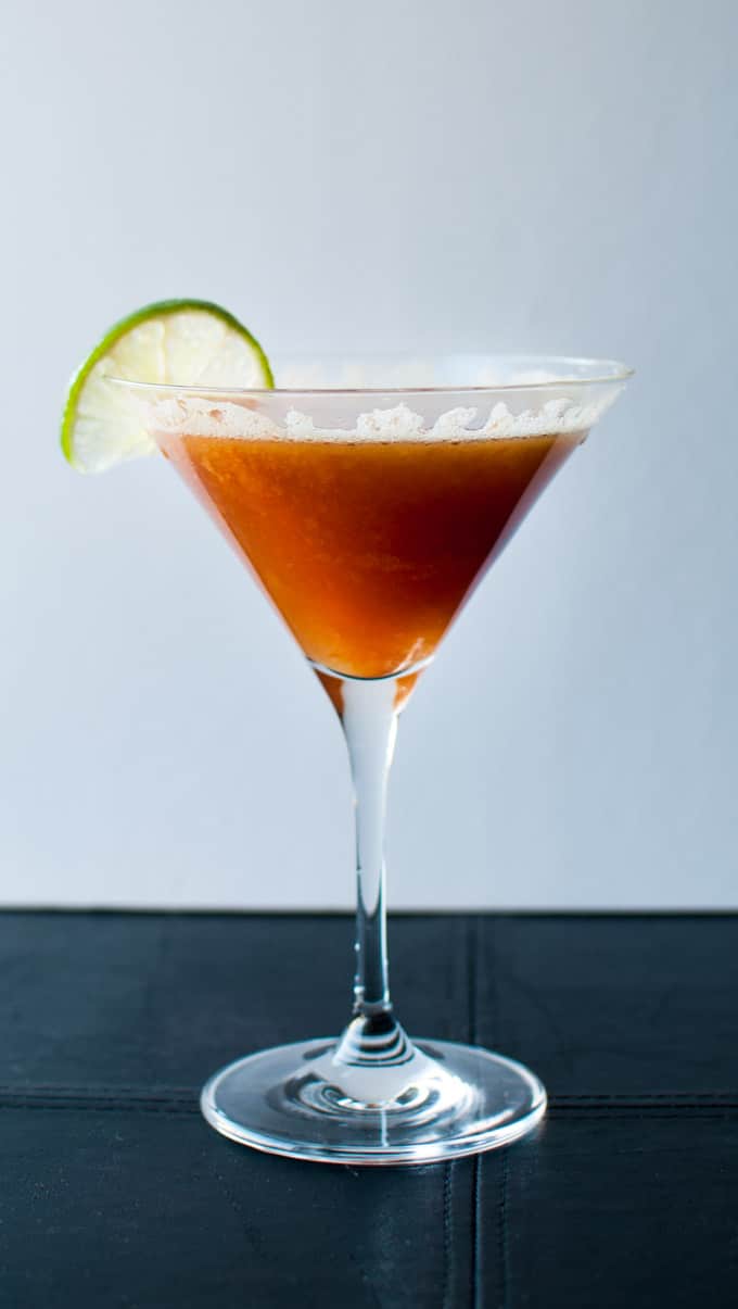 martini glass with persimmon cocktail and lime garnish