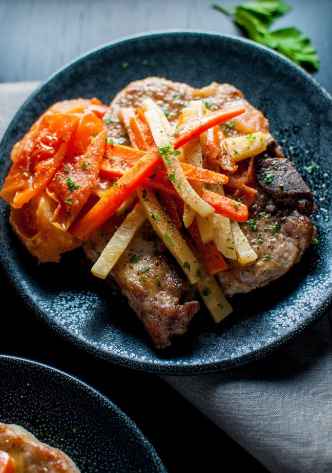 close-up of plate with pork chops with white wine, carrots, and celeriac