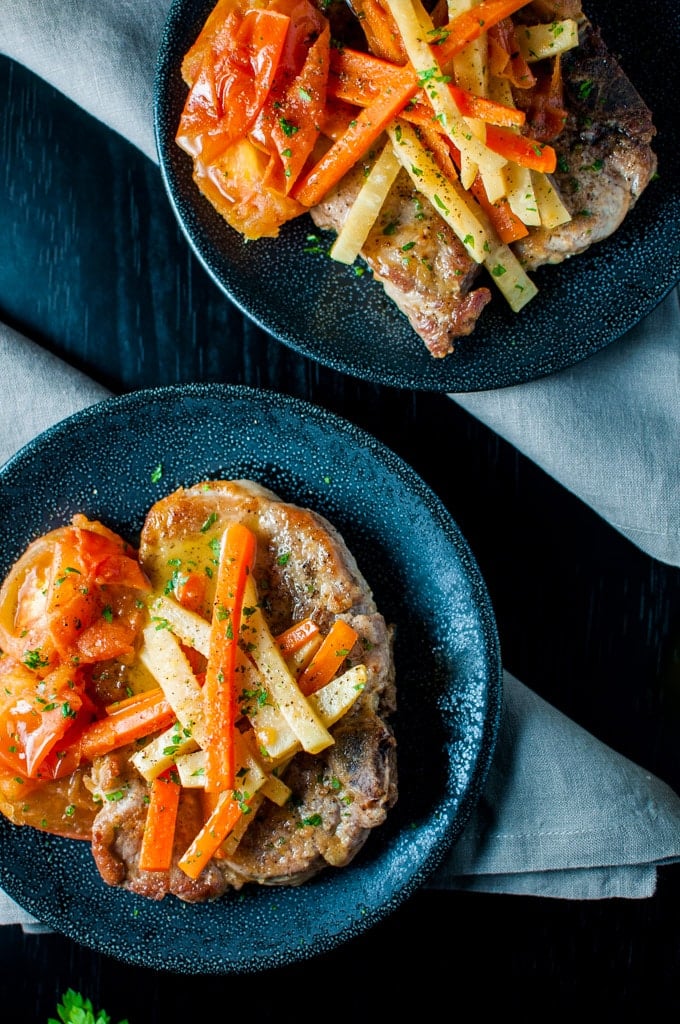 two plates of pork chops with white wine, carrots, and celeriac