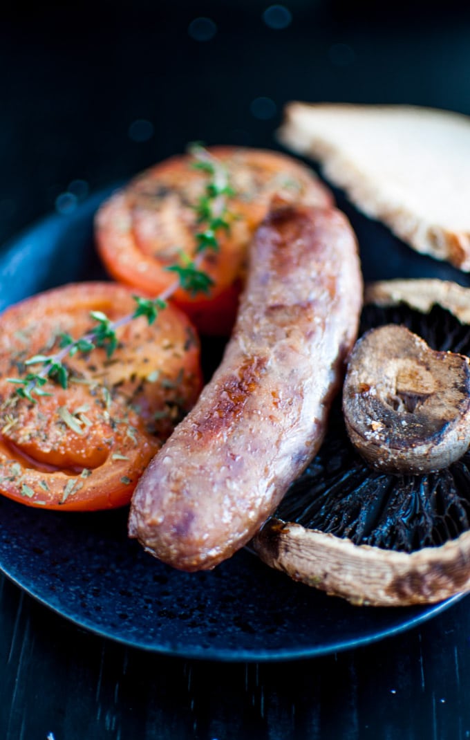 close-up of one-pan roasted sausages, tomatoes, and portobello mushrooms on a plate