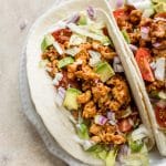 This BBQ chicken taco recipe is easy, fast, healthy, and delicious! These tacos are made with ground chicken, a delicious homemade taco seasoning blend, and BBQ sauce. Load up the flour tortillas with sour cream, onions, iceberg lettuce, and tomatoes, and you have a dinner the whole family will love.