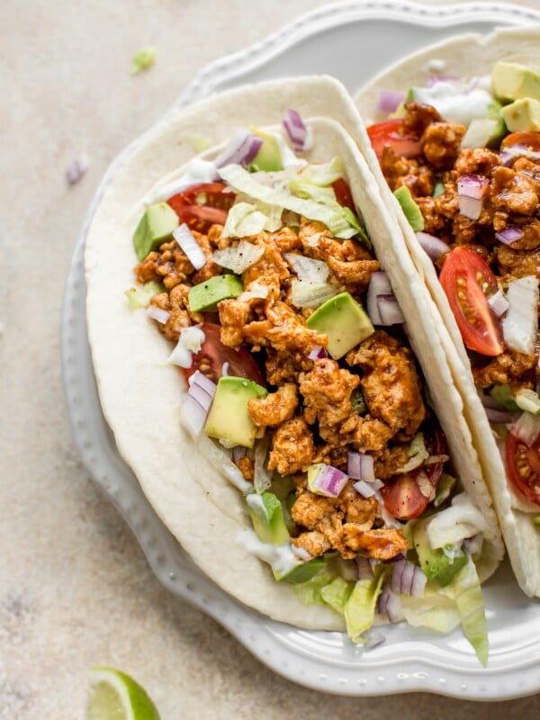 This BBQ chicken taco recipe is easy, fast, healthy, and delicious! These tacos are made with ground chicken, a delicious homemade taco seasoning blend, and BBQ sauce. Load up the flour tortillas with sour cream, onions, iceberg lettuce, and tomatoes, and you have a dinner the whole family will love.