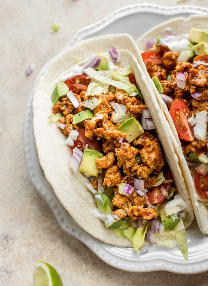 This BBQ chicken taco recipe is easy, fast, healthy, and delicious! These tacos are made with ground chicken, a delicious homemade taco seasoning blend, and BBQ sauce. Load up the flour tortillas with sour cream, onions, iceberg lettuce, and tomatoes, and you have a dinner the whole family will love.