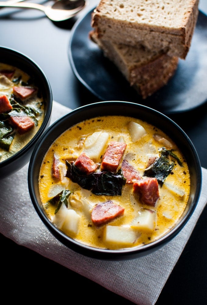 chorizo, white bean, and potato soup in a bowl with beside rye bread