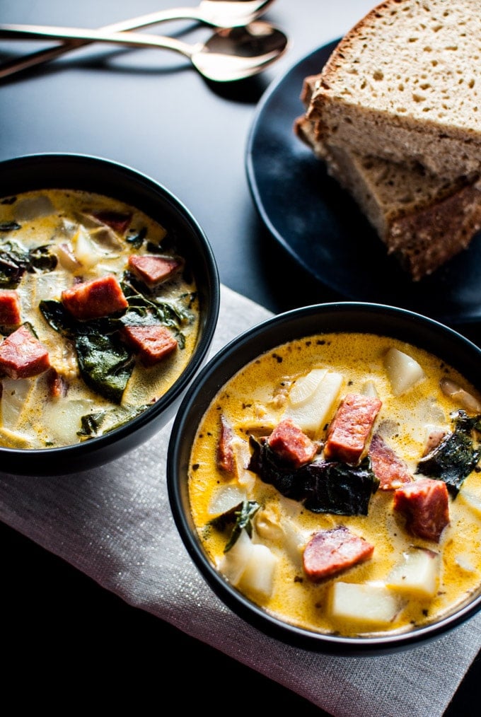 two bowls of chorizo, white bean, and potato soup with a stack of rye bread slices