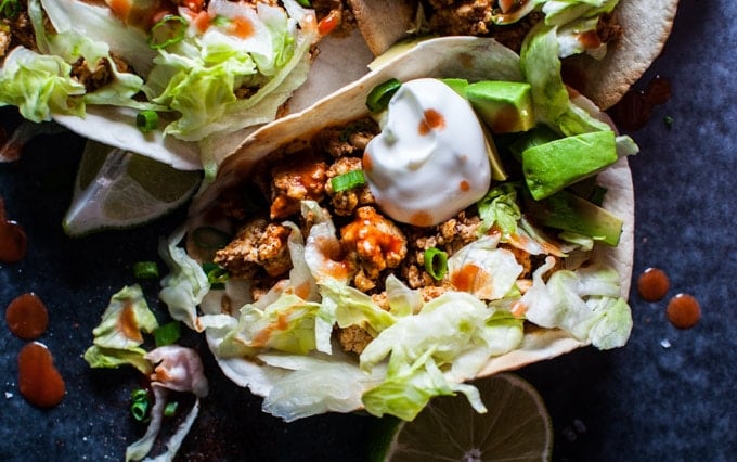 close-up of buffalo chicken tacos with avocado and sour cream