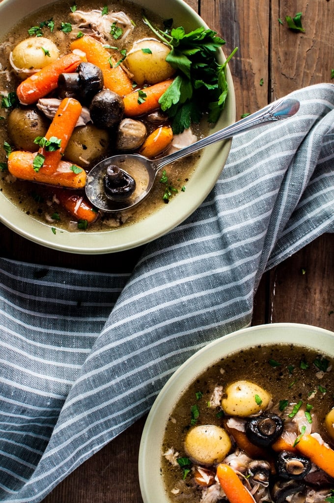 cozy Crockpot chicken stew with two bowls and a grey cloth napkin