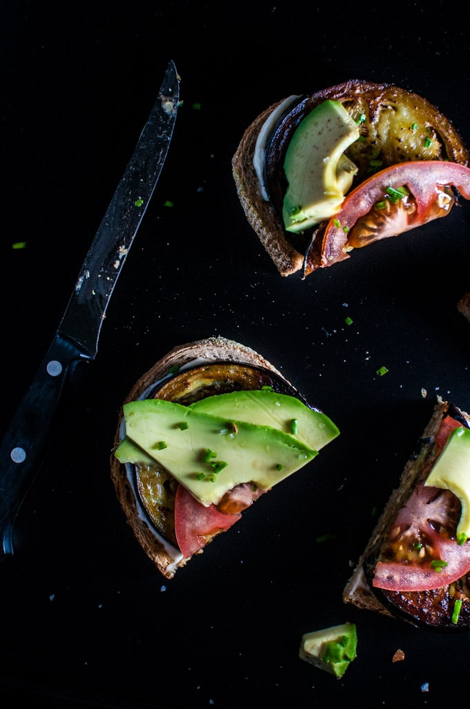 slices of vegetarian toast with avocado, tomato, and fried eggplant with a knife