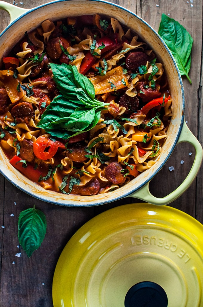 one-pot chorizo, bell pepper, and tomato noodles in a yellow pot with basil garnish