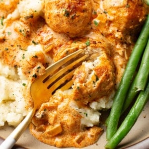 a plate with paprika chicken meatballs, mashed potatoes, and green beans
