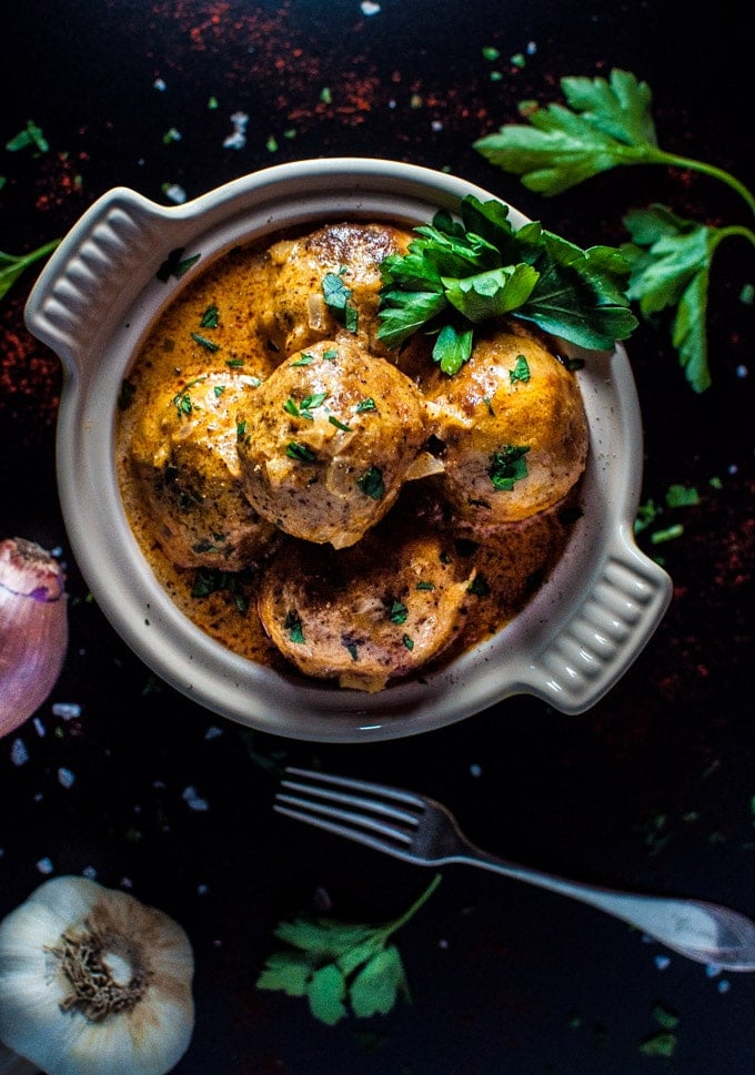 chicken meatballs with creamy paprika sour cream sauce in a bowl with parsley garnish and a fork