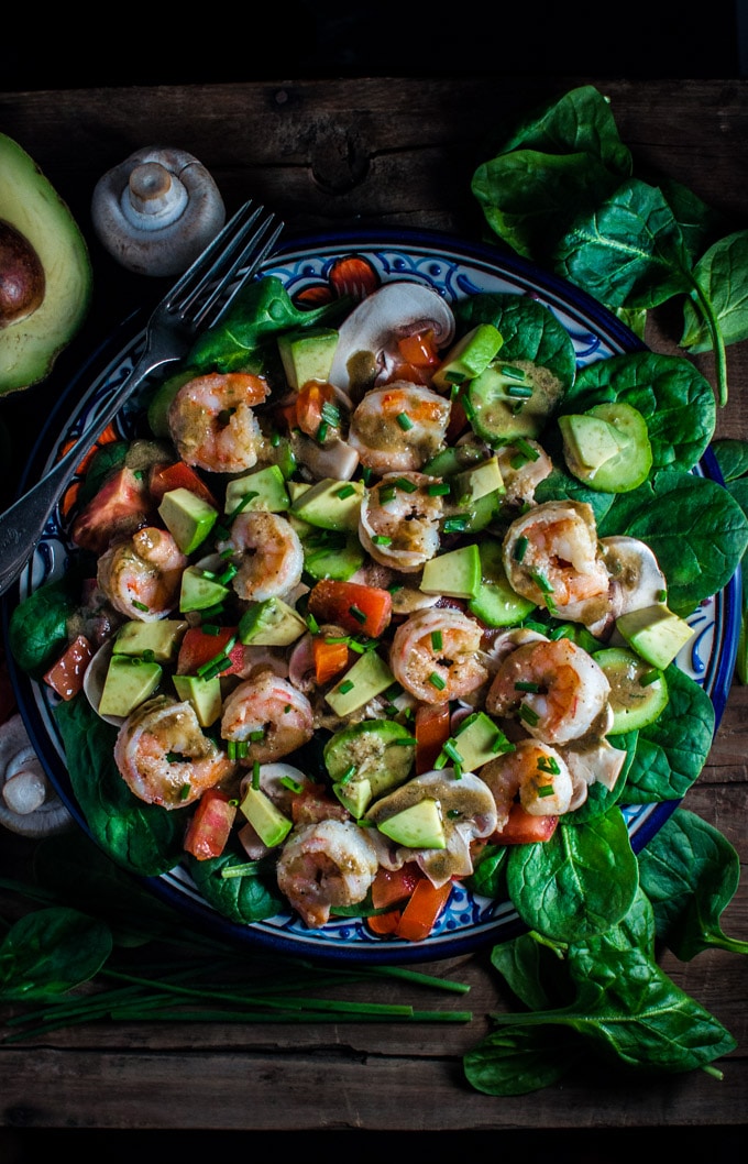spinach salad with shrimp and a smoky sweet dressing on a plate with a fork and avocado