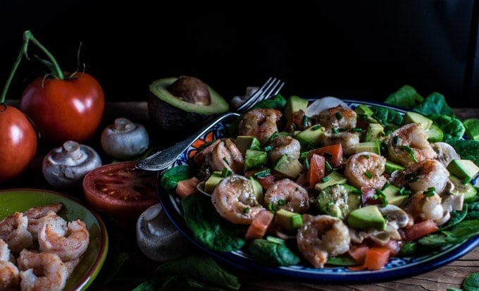 spinach salad with shrimp and a smoky sweet dressing on a table with extra ingredients and a fork