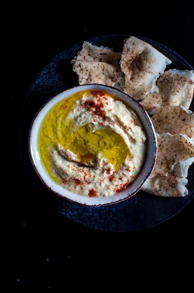 bowl of creamy lemon hummus beside pieces of pita bread