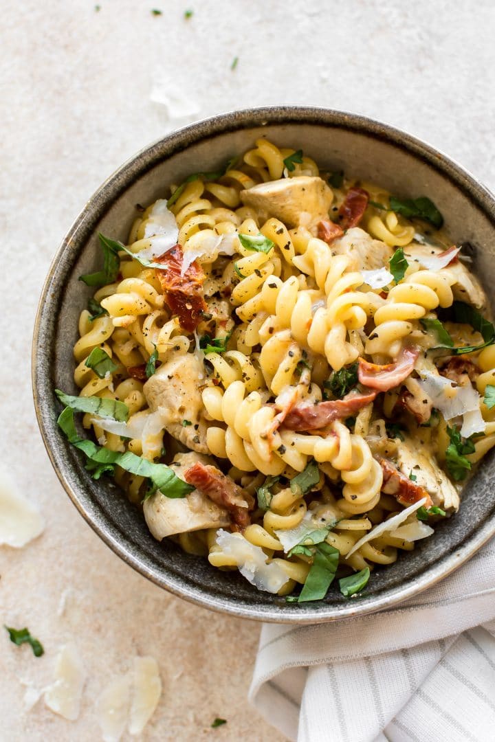 bowl of Cajun chicken pasta with sun-dried tomatoes, basil, and parmesan