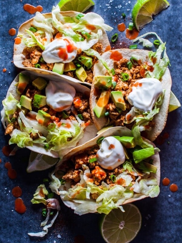 several buffalo chicken tacos with sour cream and avocado