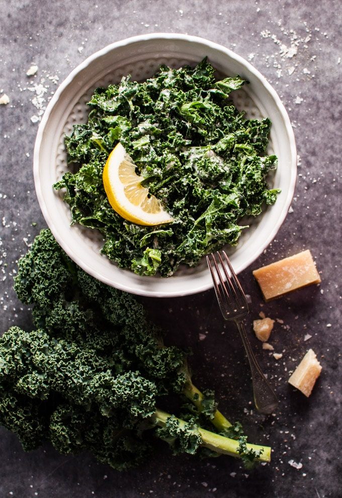 a bowl of kale salad with parmesan, lemon, and black truffle oil with a fork