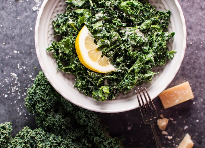 bowl of kale salad with parmesan, lemon, and black truffle oil with a fork