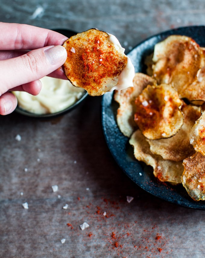 a hand holding a small batch microwave potato chip dipped in homemade truffle mayo